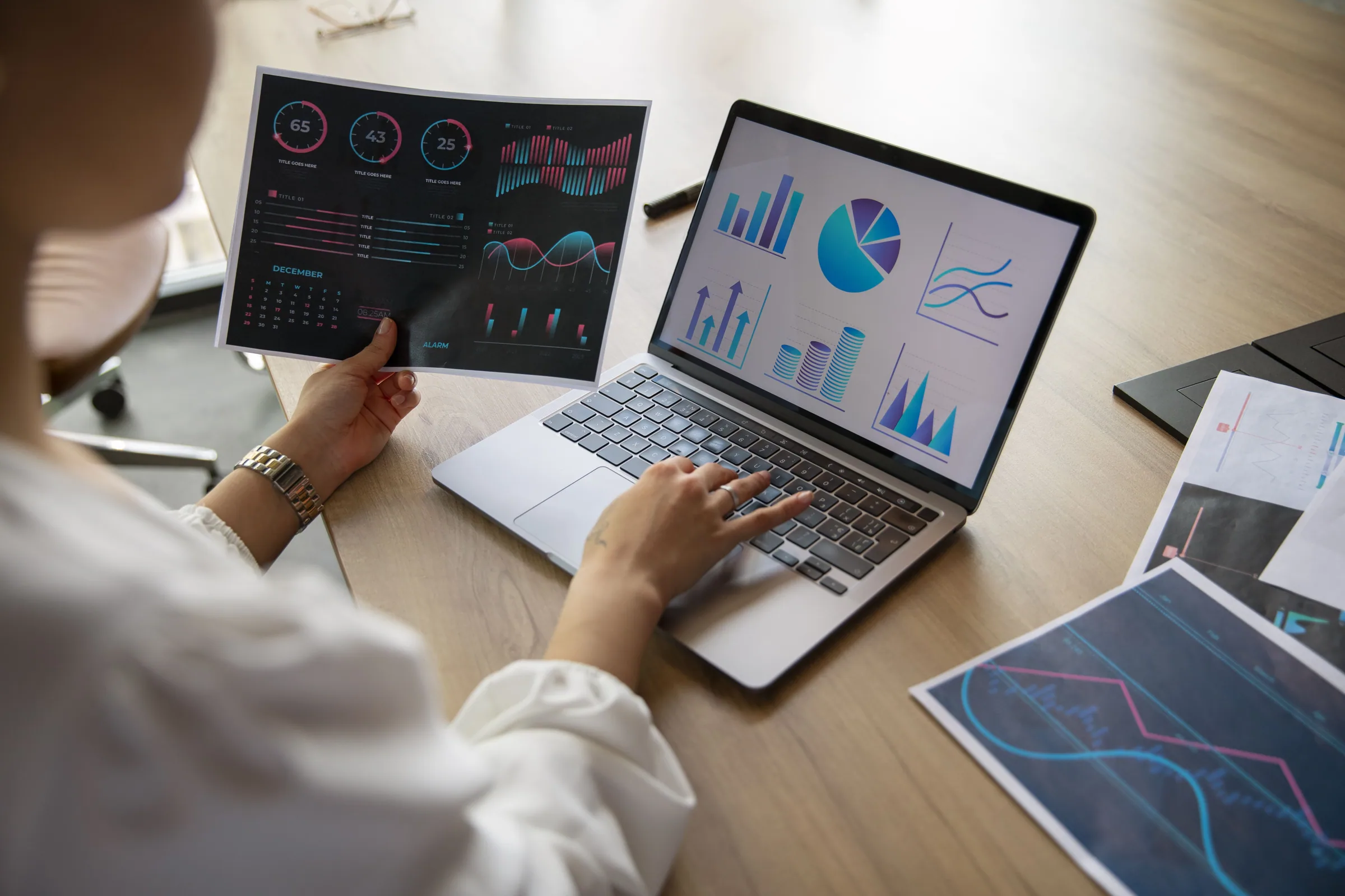 Business analyst reviewing digital dashboards and data visualization charts, and printed reports for strategic decision-making.