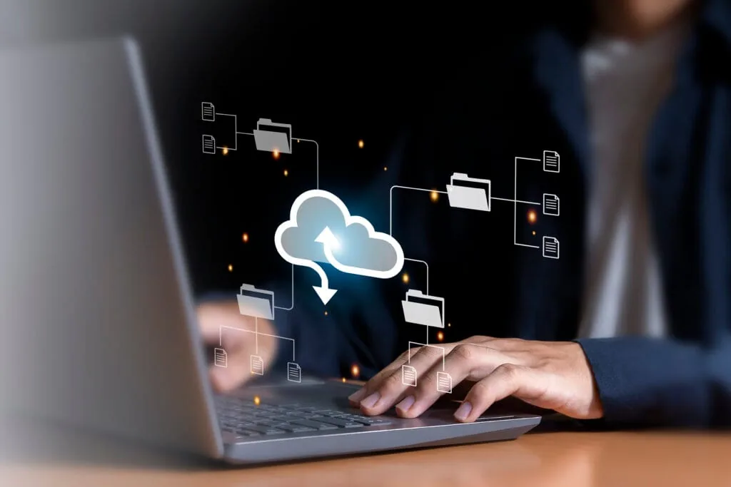 Person using a laptop to manage cloud data migration with digital file folder icons representing cloud storage solutions.