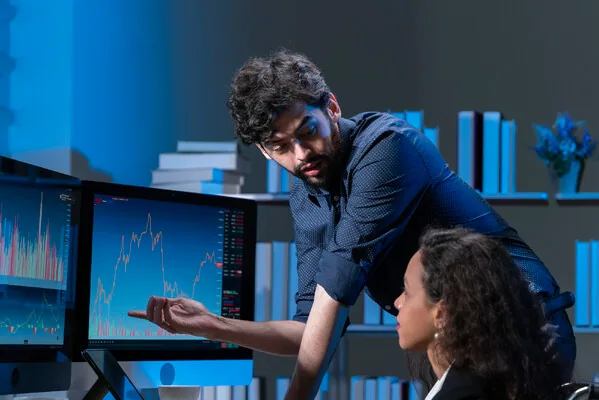 Financial analyst explaining stock market trends on monitors—AI-powered fintech solutions in action.